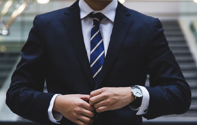 A lawyer buttoning his jacket in front of some stairs.