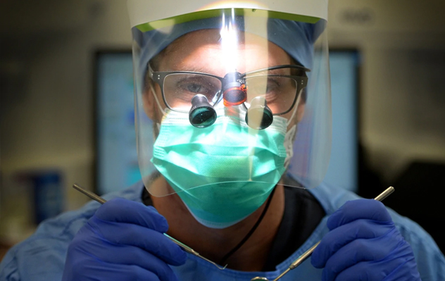 A dentist performing teeth cleaning with the aid of a dental assistant