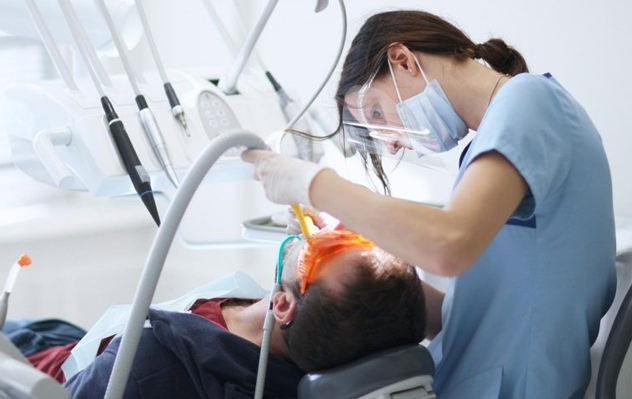 A dental assistant wearing their uniform and standing in a dentist’s office