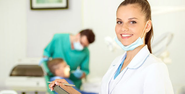 A dental assistant smiling while holding a clipboard