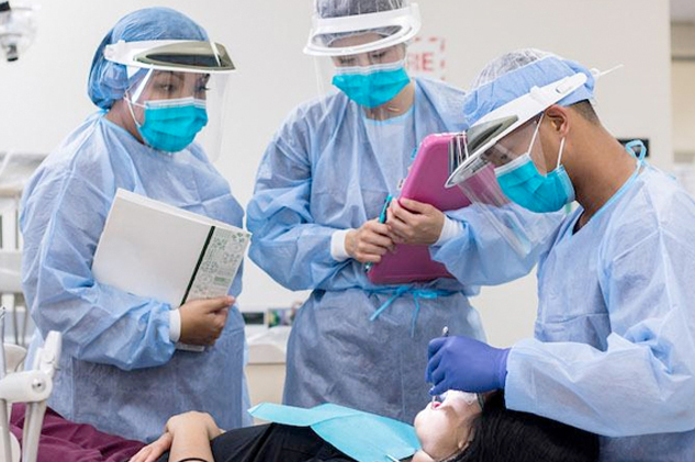 A dental assistant adjusting the dental operatory lamp above the patient