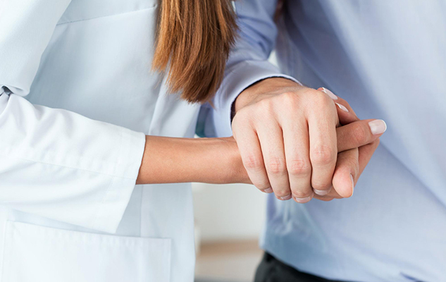 Closeup of a personal support worker holding a client’s hand
