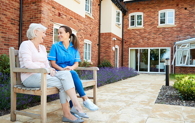 Community support worker and an elderly woman talk on a bench