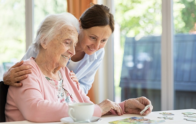 A personal support worker playing puzzles with an elderly client