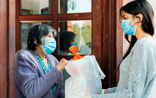 Caregiver bringing groceries to a woman at her home