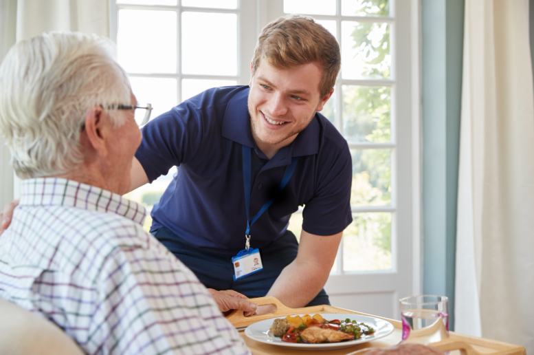 Personal support worker serving a meal to an elderly patient