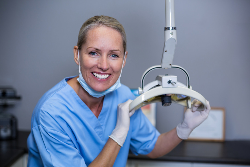 A person wearing scrubs and gloves holding a microscope