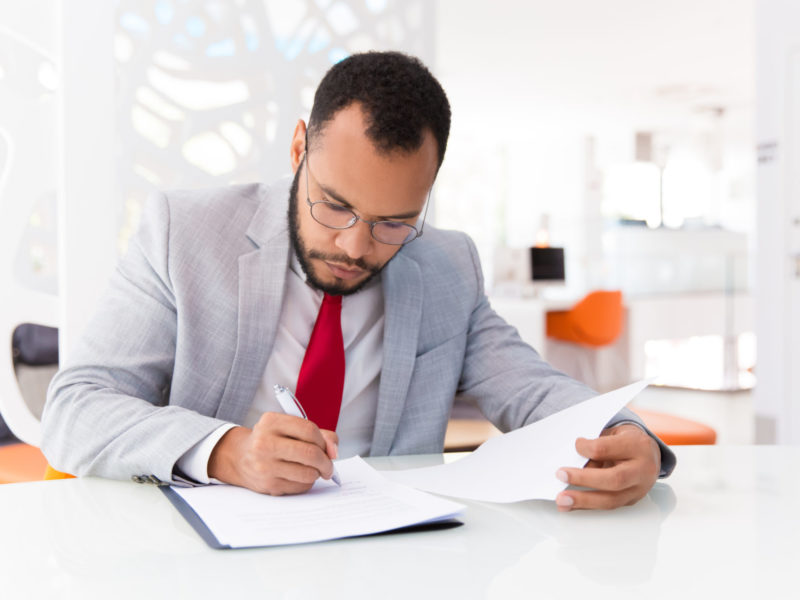 Focused,Auditor,Checking,Document.,Business,Man,Wearing,Suit,And,Eyeglasses,