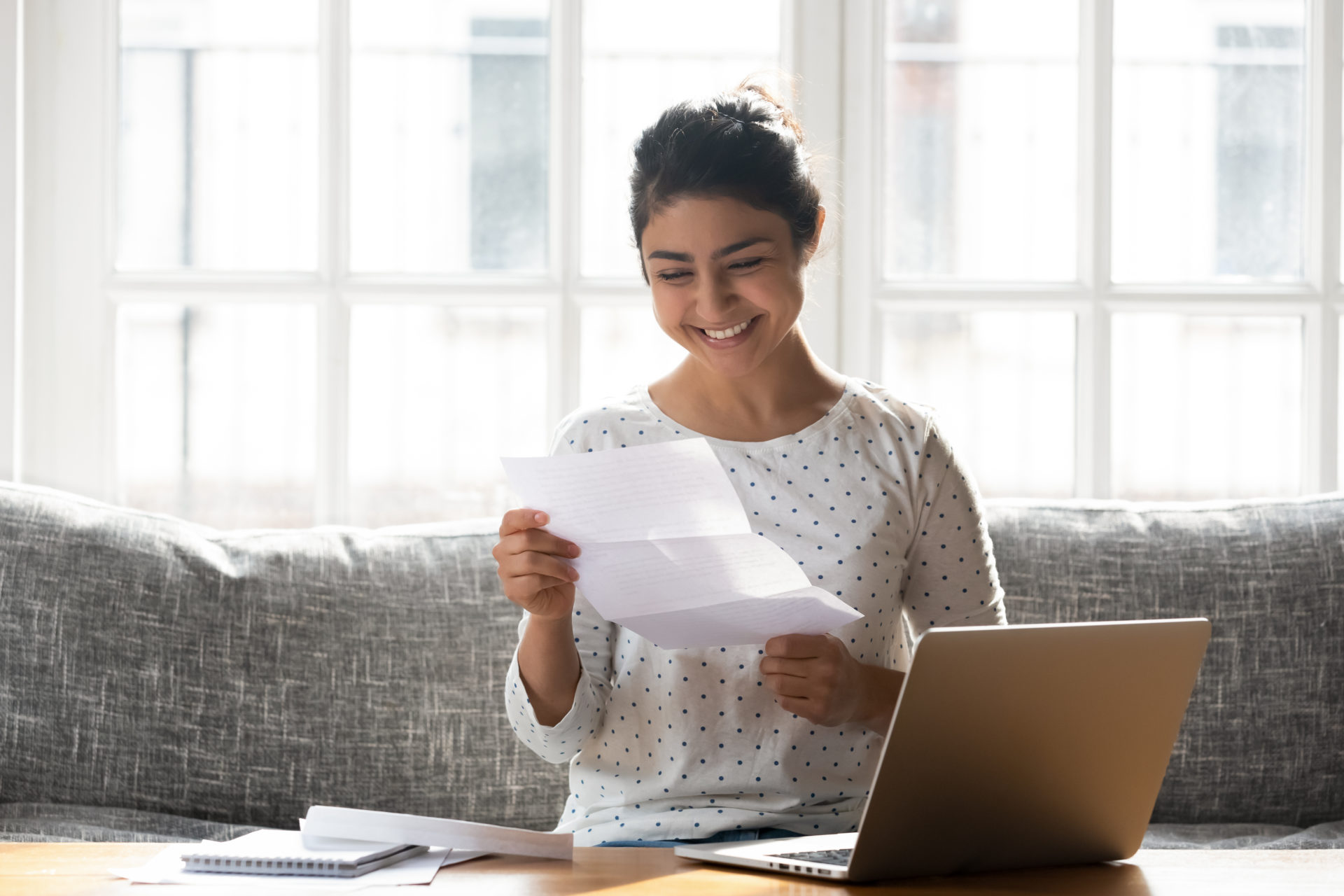 Indian,Ethnicity,Woman,Sitting,On,Couch,At,Home,Reading,Paper