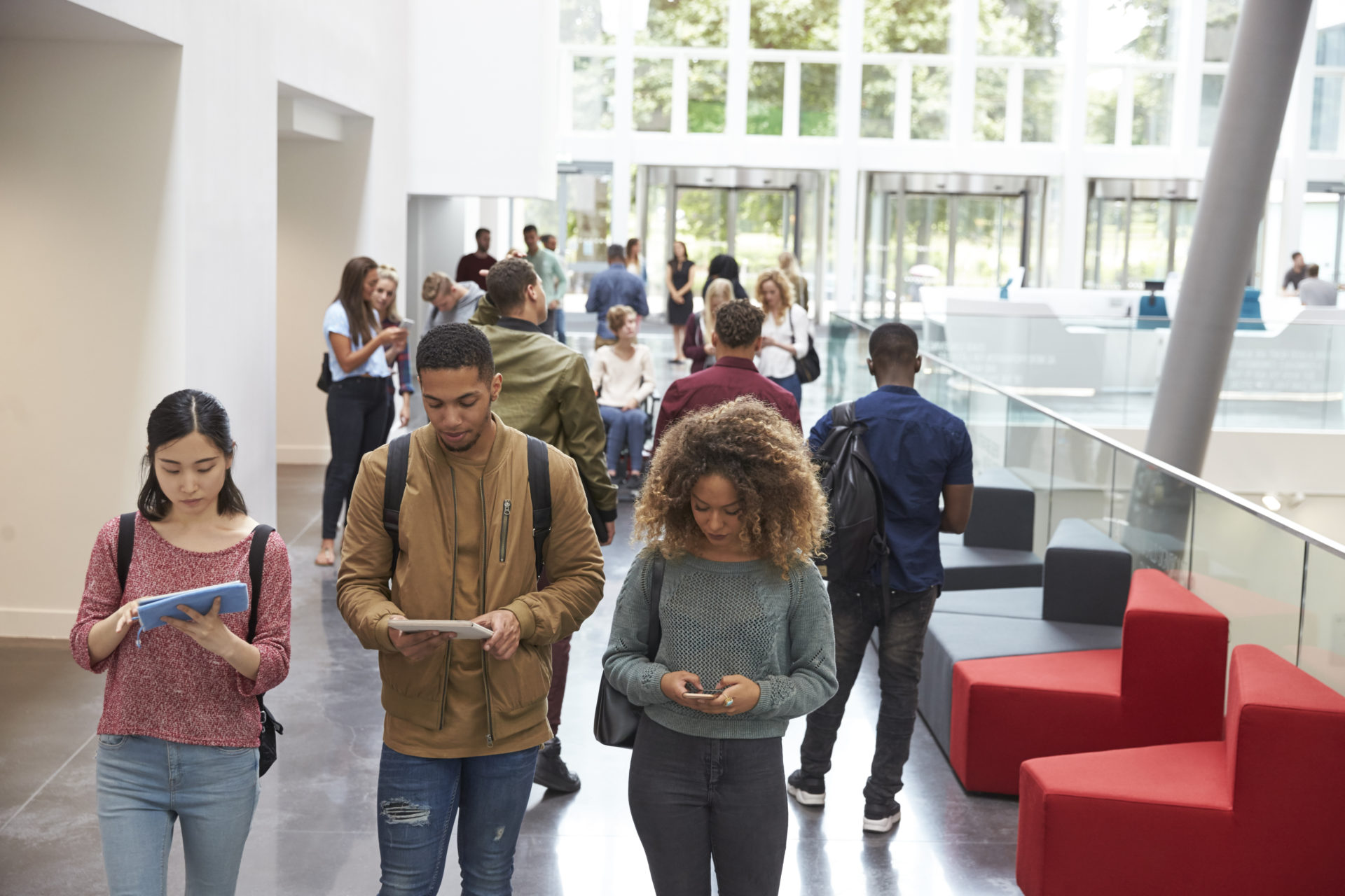 Students,Walk,In,University,Campus,Using,Tablets,And,Phone
